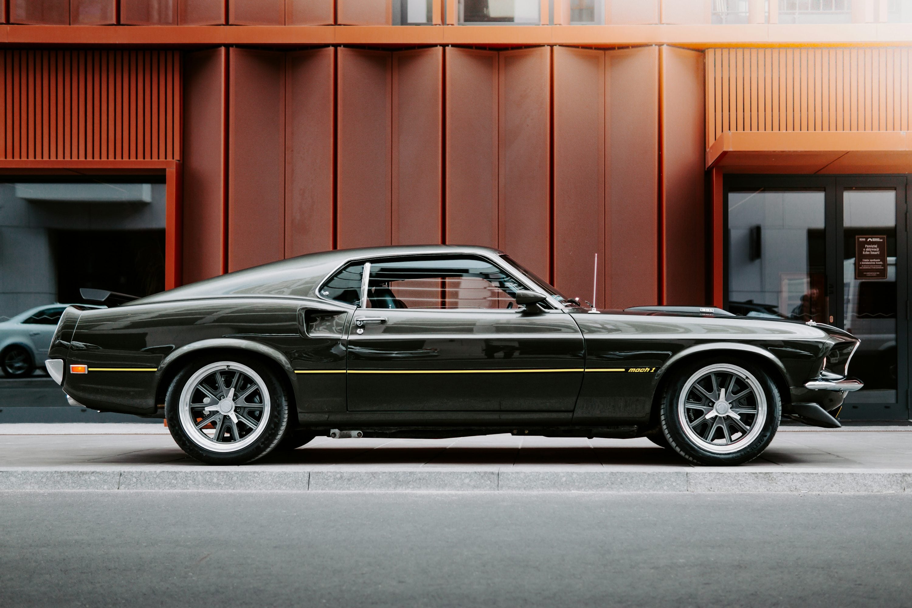 Classic American coupe parked in front of an industrial building